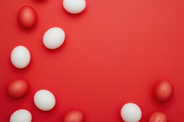 Bright red backdrop with scattered red and white Easter eggs, flat lay top view with copy space
