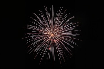 Stunning pyrotechnics illuminating the night sky during a festive event, featuring bright lights and star shapes on a dark backdrop