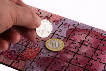 A puzzle piece of a 100 yuan bill, 10 yuan coin and a 1 yuan coin