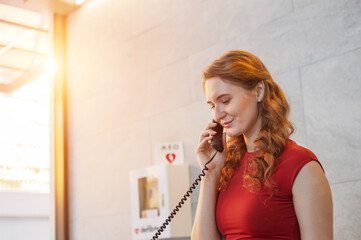 Hotel reception on the phone. Female receptionist taking telephone call  while standing at counter in hotel lobby.