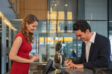 The Hotel receptionist and guest are filling out paperwork while checking in at hotel reception desk. staff serving a foreign visitor.