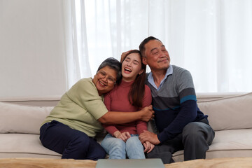 Asian parents and children sit on the sofa talking happily and joyfully.