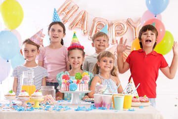 Birthday celebration. Kids at table with tasty cake and different treats in festive decorated room