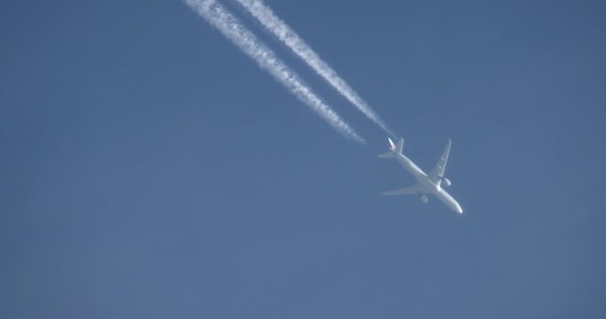 Airliner at 10000 m with contrails, static upward telephoto view, passenger jet underside, clear blue sky, recorded 100 fps slow motion 25 fps