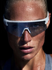 A young sweaty woman wearing running sunglasses stands resting after a run. Cardio exercise and active sports.
