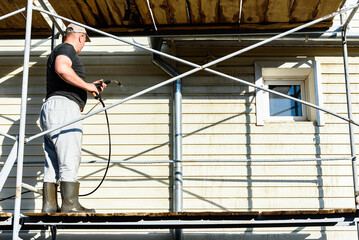 Cleaning the vinyl siding wall with a high-pressure washer.