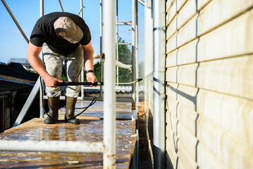 Cleaning the vinyl siding wall with a high-pressure washer.