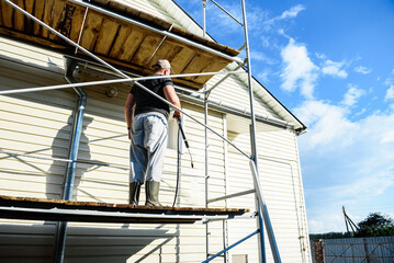 Cleaning the vinyl siding wall with a high-pressure washer.