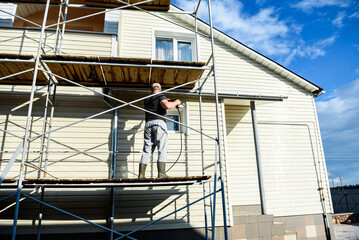 Cleaning the vinyl siding wall with a high-pressure washer.
