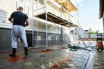 Cleaning the vinyl siding wall with a high-pressure washer.