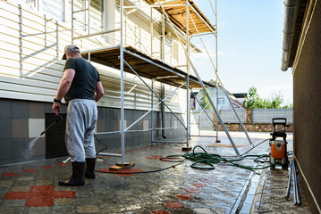 Cleaning the vinyl siding wall with a high-pressure washer.