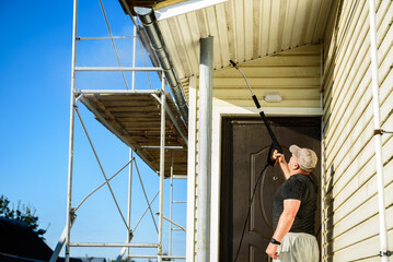 Cleaning the vinyl siding wall with a high-pressure washer.