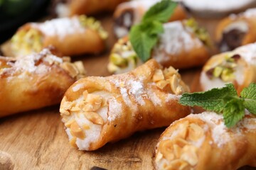 Delicious cannoli with cheese, nuts, powdered sugar and mint on table, closeup