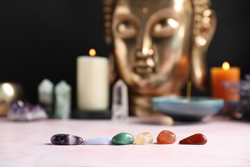 Chakra gemstones on table with candles and Buddha figure, selective focus