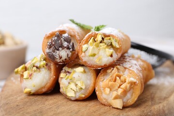 Delicious cannoli with cheese, nuts, powdered sugar, chocolate and mint on table, closeup