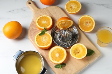 Squeezer with oranges, mint and fresh juice on white table, flat lay