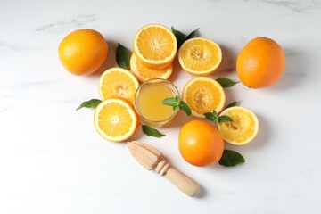 Freshly squeezed orange juice, fruits and juicer on white table, flat lay