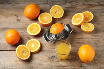 Freshly squeezed orange juice, fruits and juicer on wooden table