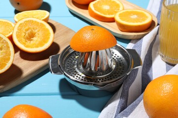 Squeezer, oranges and fresh juice on blue wooden table, closeup