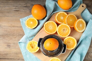 Squeezer and oranges on wooden table, flat lay. Making fresh juice
