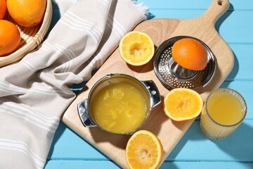 Freshly squeezed orange juice, fruits and juicer on blue wooden table, flat lay