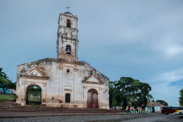 Historic church in Trinidad, Cuba under cloudy sky.
