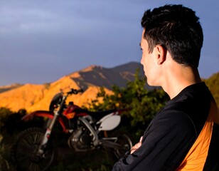 Man looking at motocross bike in mountains at sunset