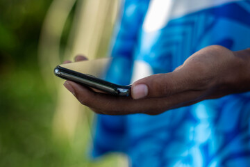 Closeup of a hand holding a smartphone with a blurred green background