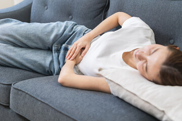 Sick asian young woman in pain, hand holding belly, stomach pain from food poisoning, girl hurt...