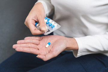 Sick ill asian young woman, girl hand taking tablet pill capsule out from blister pack, painkiller...
