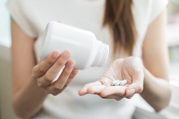 Sick asian young woman, girl holding tablet pill on hand pouring drug from medication bottle,...