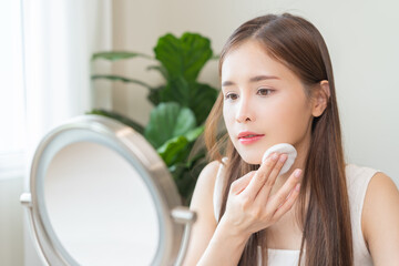 Remove makeup, attractive asian young woman, girl looking into mirror, hand holding cotton pad,...