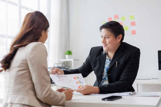 Businessman presenting positive data charts to businesswoman during an office meeting, highlighting key insights for growth and success