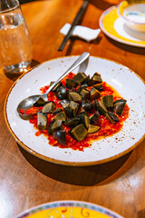 Chinese appetizer of century eggs sliced and served over a bed of minced red chili peppers in a rustic ceramic plate on a wooden table
