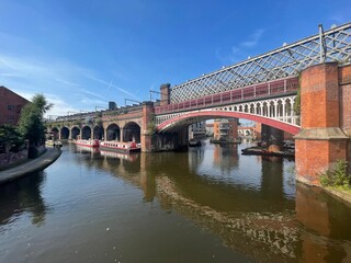 Historic railway bridge over canal with boats in Manchester