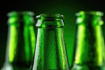 Close-up of three green beer bottles.  Focus on necks and caps.  Condensation visible