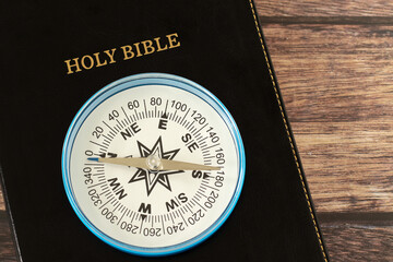 Compass on holy bible book with wooden background. Top view. Christian biblical concept of...