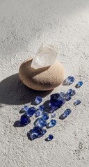 Clear quartz crystal atop a stone, surrounded by scattered blue gems