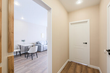 view through a doorway shows a modern apartment interior. The hallway features a closed white door,...