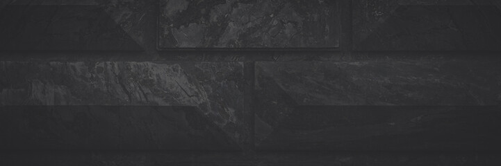 Wall lined with decorative stone with a beautiful natural pattern. Faded dark wide panoramic...