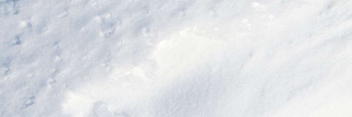 Beautiful winter background with snowy ground. Natural snow texture. Wind sculpted patterns on snow surface. Wide panoramic texture for background and design.