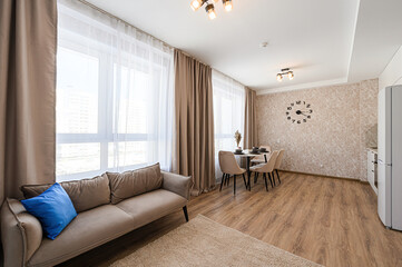 modern living space with a sofa, dining area, and large windows, bathed in natural light