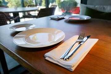 A new clean plate and new clean cutlery on the table in the restaurant.