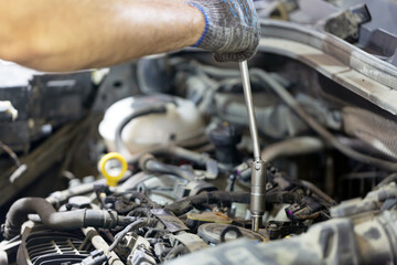 Auto mechanic man checks an old used spark plug in the car. Car maintenance concept