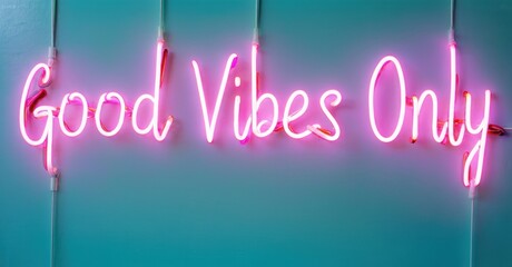 Bright pink neon sign displays Good Vibes Only against teal wall. Simple, positive message radiates cheerful energy. Minimalist aesthetic.