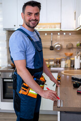 Skilled worker measuring countertop in modern kitchen during home improvement project