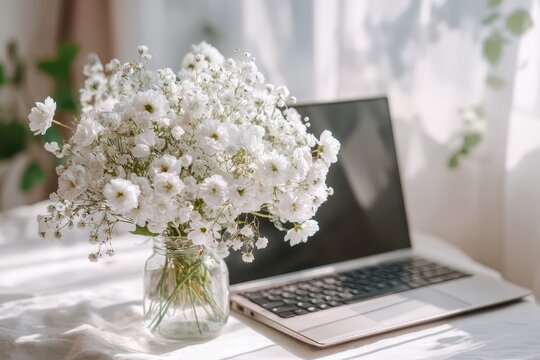 White flowers and laptop on a sunlit desk, creating a calm home office vibe. - Powered by Adobe