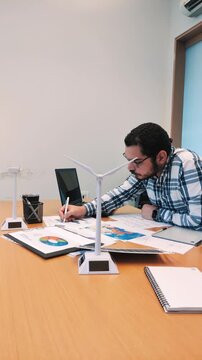 Male Architect Cross-Referencing Documents for a Sustainable Project