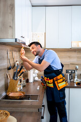 Technician performs maintenance on kitchen appliances in modern home during the day