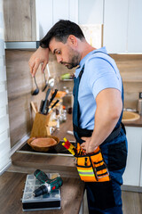 Man engaged in home repair work in a modern kitchen setting during daytime